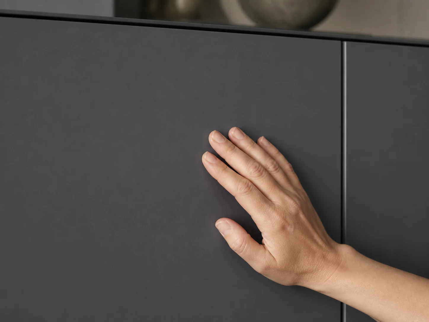 A hand touches a clean graphite matt front surface
